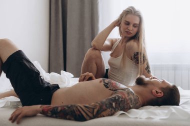 Her bir yatakta dövmeli genç çift yan görünüm