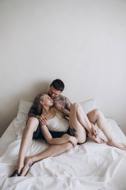 Genç dövmeli çift sensually yatağa kucaklayan