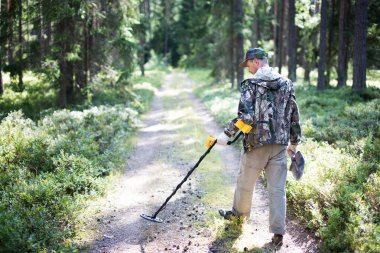 Ormanda metal detektörü ve küreği olan hazine avcısı.