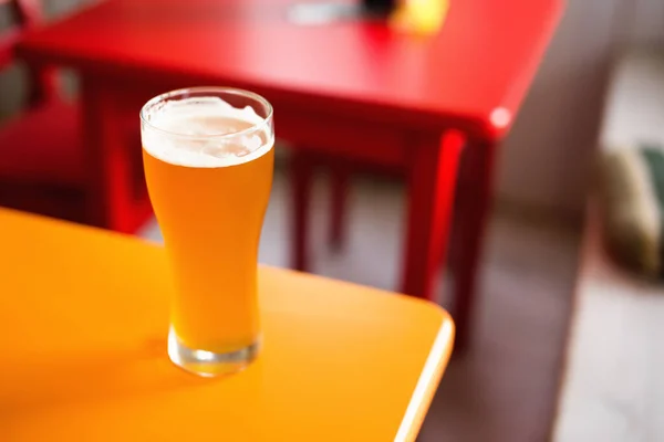 Glass of craft beer pale ale APA on colorful table in hipster bar. Shallow depth of field. Top angled view