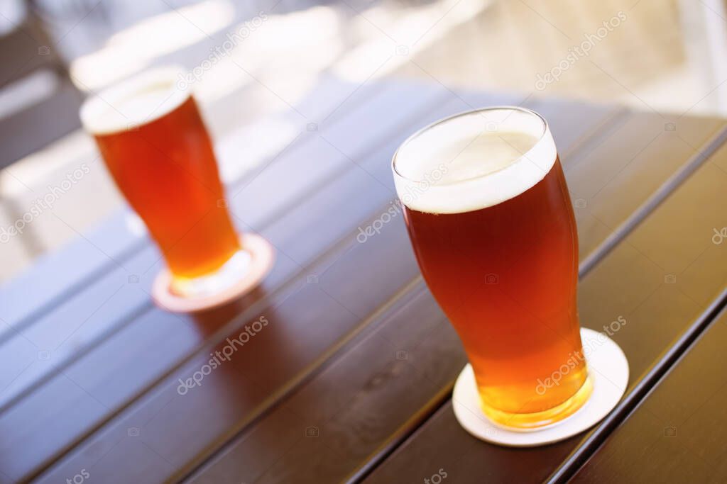 Two glasses of delicious crafted IPA style beers on a table. Shallow depth of field.