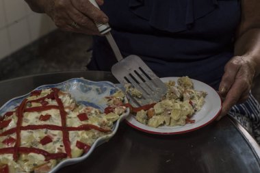 Yaşlı kadın günlerini karantinada patates salatası ve biberli mayonez pişirerek geçiriyor.