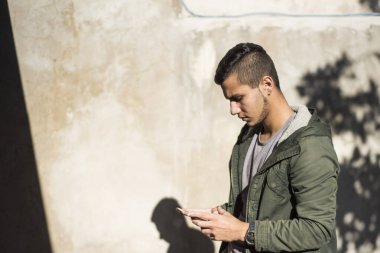 Latin genç adam akıllı telefonuyla yeni bir teknoloji kullanıyor.