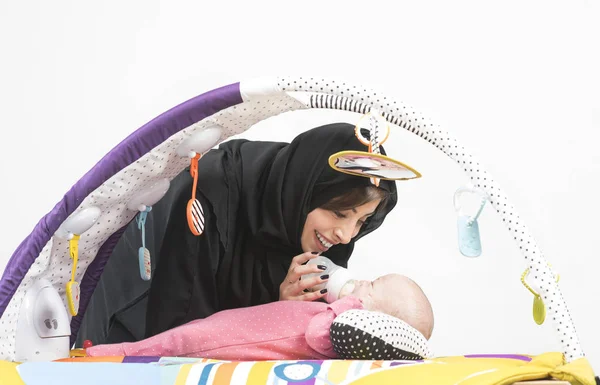阿拉伯母亲喂养她的宝贝女儿上弹垫 — 图库照片