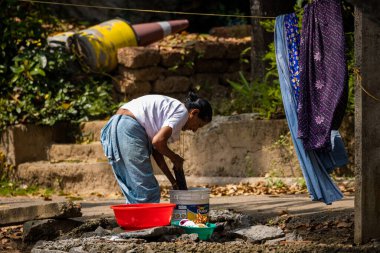 Kochi, India - 19th November 2019: Indian woman hand washing clothes outside in bucket