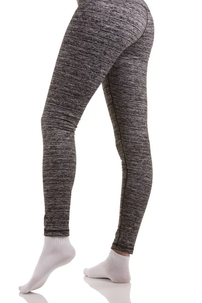 Sexy back view de pernas de mulher apto em meias brancas de pé em uma perna e outra dobrada no joelho em calças térmicas estampadas cinza — Fotografia de Stock