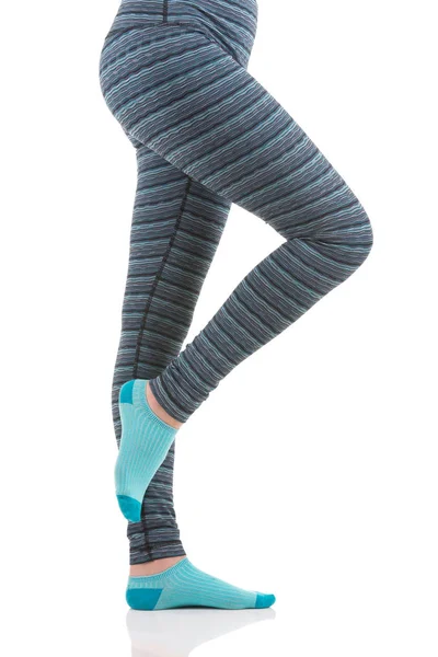 Närbild bild av kvinna ben i färgglada randiga thermal byxor och blå strumpor från vyn sida stående på ett ben med andra ledde upp — Stockfoto