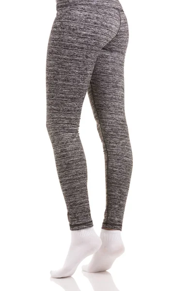 Sexy back view of fit woman legs in white socks standing on toes with one leg bended in grey patterned thermal pants — Stock Photo, Image