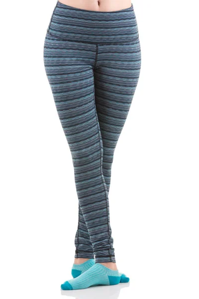 Close up view of fit woman legs wearing colourful striped sports trousers and blue socks from front view in crossing position — Stock Photo, Image