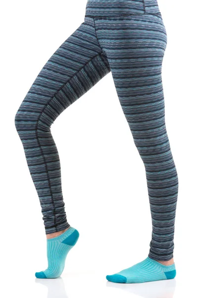 Närbild bild av kvinna ben i färgglada randiga thermal byxor och blå strumpor från vyn sida stående på ett ben med andra böjda på knä benet Royaltyfria Stockbilder