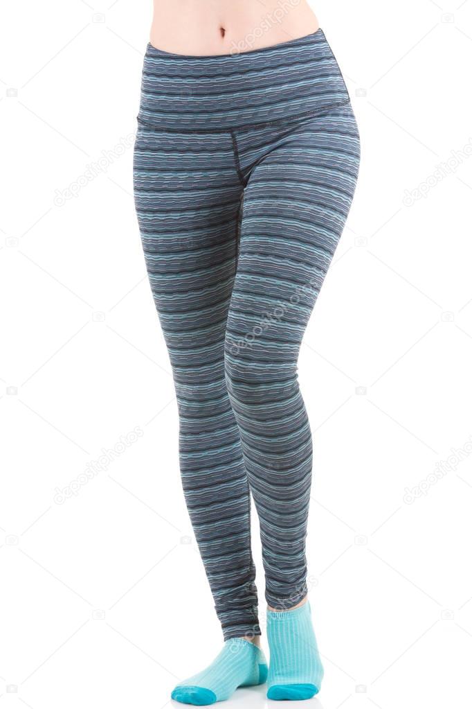 Close up view of fit woman legs wearing colourful striped sports trousers and blue socks from front view with one leg raised at the toe