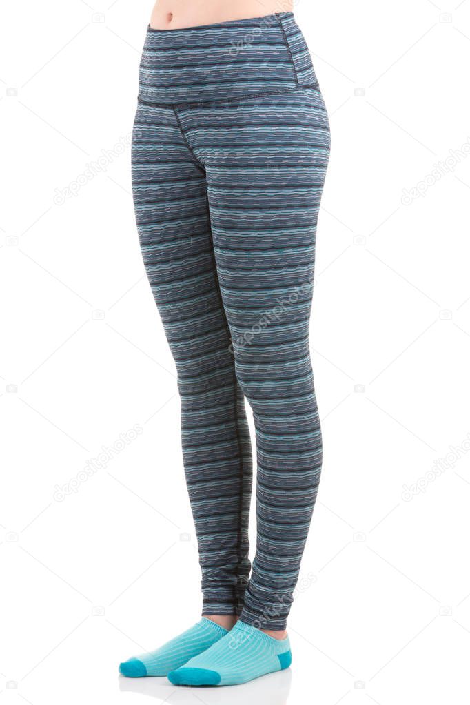 Close up view of fit woman legs wearing colourful striped sports trousers and blue socks from side view in standing foot to foot position