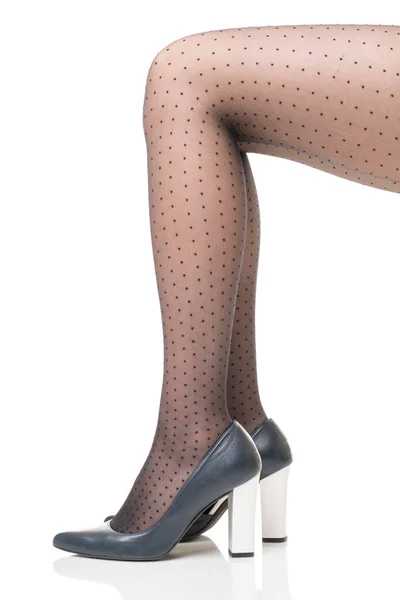 Pernas femininas em meias pretas com bolinhas e em sapatos azuis escuros com saltos brancos altos — Fotografia de Stock