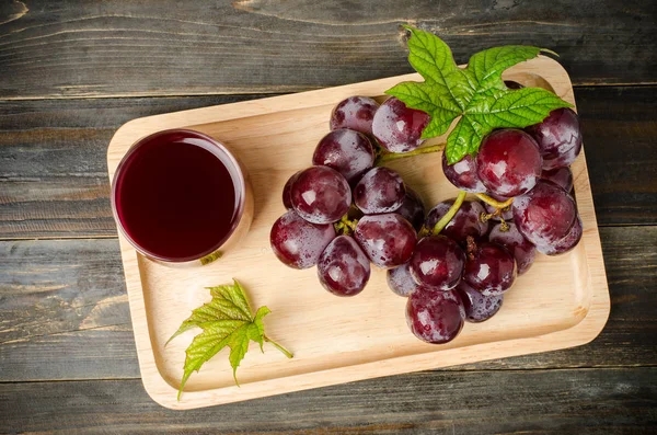 Red grapes and juice on wooden plate — Stock Photo, Image