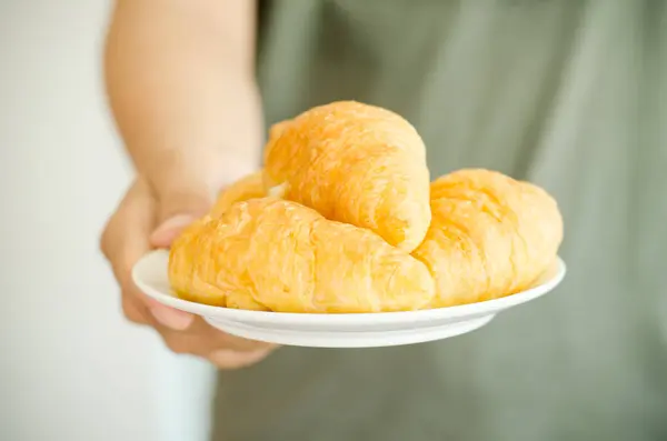 Croissant pada piring putih di tangan — Stok Foto