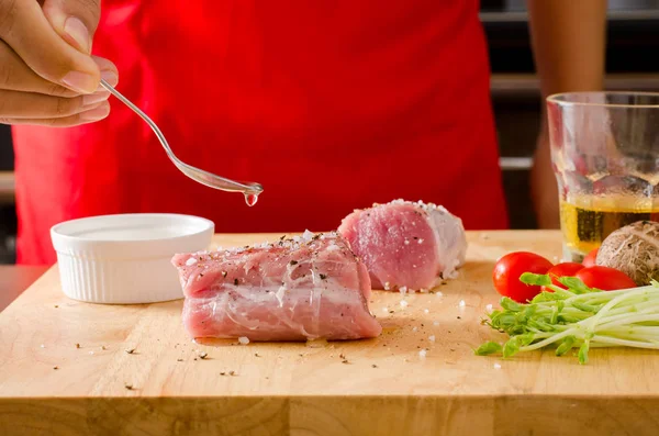 Kochhand gießt Öl auf rohes Schweinefleisch — Stockfoto