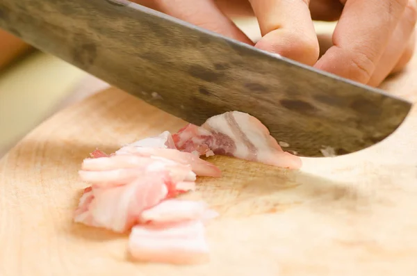 Kocken slice randigt fläsk på träskiva för matlagning — Stockfoto