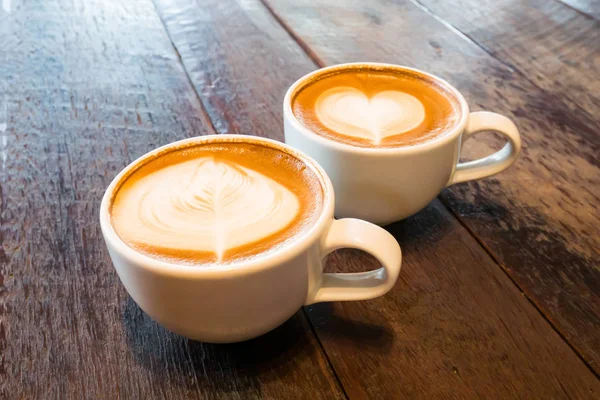 Deux tasses de café latte art sur table en bois — Photo