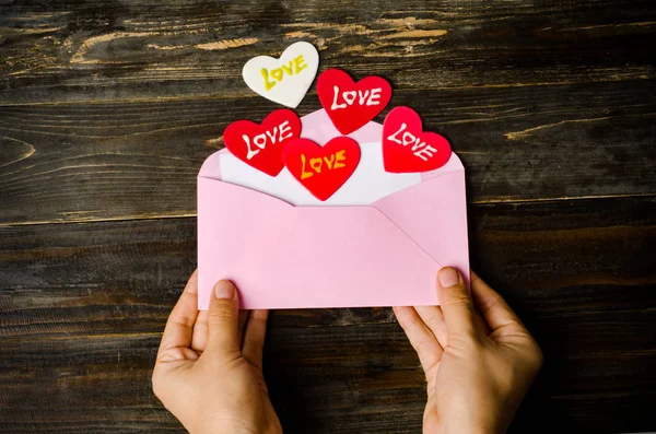Розовый конверт и красное сердце на деревянном фоне — стоковое фото