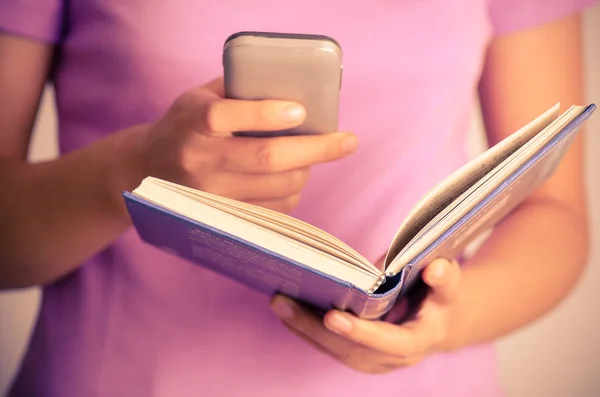 Vrouw met behulp van slimme telefoon voor search on boek — Stockfoto