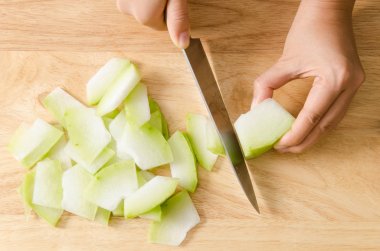 Chef cutting wax gourd on wooden board  clipart