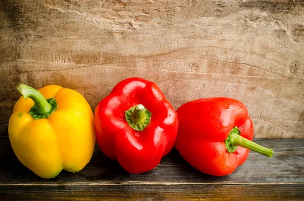 Gelbe und rote Paprika auf hölzernem Hintergrund — Stockfoto