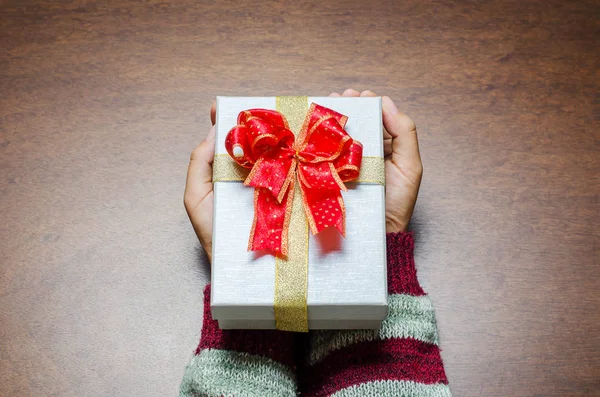 Woman holding gift box by hand for giving in holidays