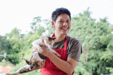 Asya adam kedi ile oynarken kırmızı önlük giymek