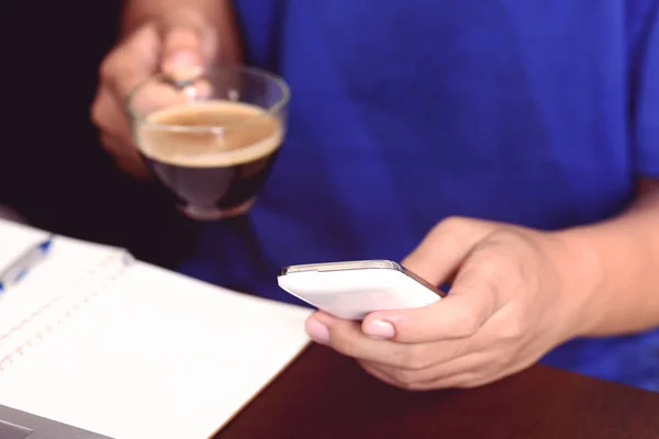 Hombre usando el teléfono inteligente para trabajar y beber café — Foto de Stock