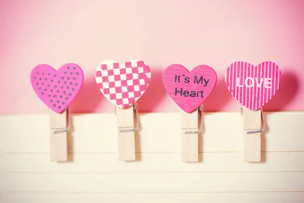 Decoração roupas pegs (forma de coração) com papel sobre fundo rosa — Fotografia de Stock