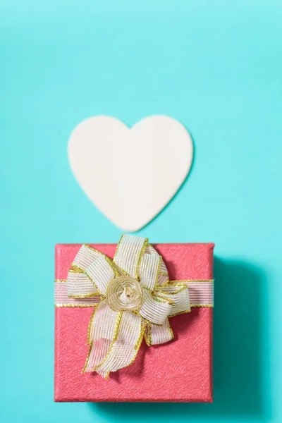 Червона подарункова коробка та біле серце на зеленому пастельному фоні — стокове фото