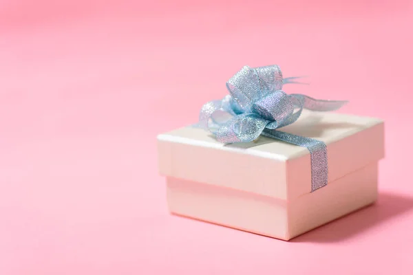 Caja de regalo de plata con cinta azul sobre fondo rosa —  Fotos de Stock