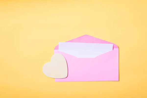 Rosafarbener Umschlag mit weißer Karte innen und Herz — Stockfoto