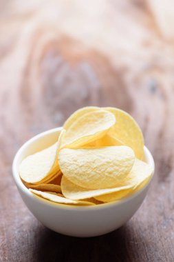 Ahşap arka plan üzerine bir kase içinde patates cipsi
