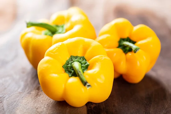 Yellow bell peppers or sweet peppers on wooden background