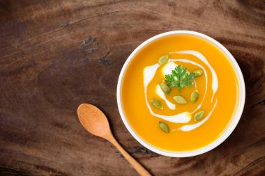 Kabak çekirdeği ve kremalı kabak ezmesi çorbası ahşap arka planda.