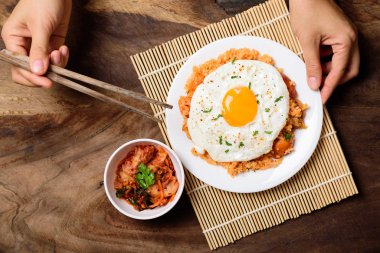 Kızarmış pilav, kızarmış yumurta ve ahşap arka planda kimçi lahana yemek için çubuk tutmak, Kore yemeği, üst görüş.