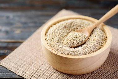 Kase içinde kaşık ile çiğ kahverengi kinoa tohumu