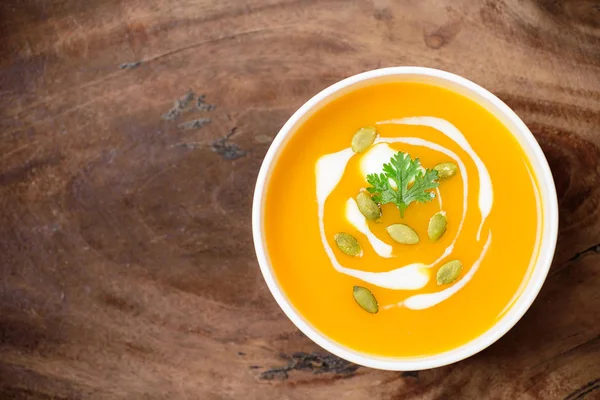 Kabak tohumlu kabak ezmesi çorbası ve ahşap arka planda krema.