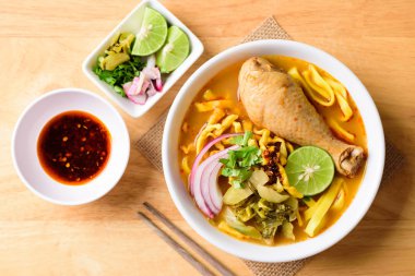 Kuzey Tayland yemeği (Khao Soi Kai), baharatlı yumurtalı erişte çorbası, tavuk ve bol yağda kızartılmış yumurta eriştesi, turşulu hardal yeşili, soğan soğanı, limon, kişniş yaprağı ve yağda kızartılmış kırmızı biber karışımı.