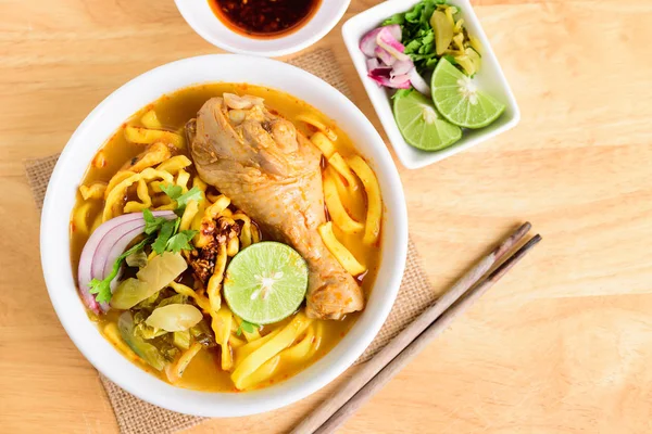 Northern Thai food (Khao Soi Kai), spicy egg noodles soup with chicken and mix ofdeep-fried egg noodles, pickled mustard greens, shallots, lime, coriander leaves and ground chillies fried in oil
