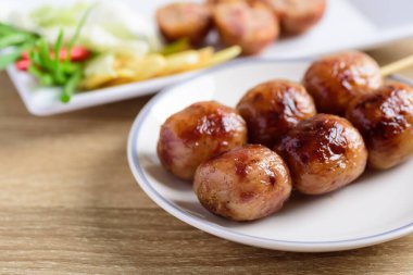 Tayland sosisi ya da Isan sosisi, ızgara mayalanmış pirinç ve domuz eti taze zencefil, lahana ve kırmızı biberle yenir.