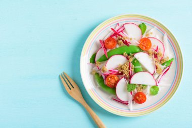 Sağlıklı sebze salatası. Dilimlenmiş turp, domates, yeşil bezelye ve kinoa tohumu.