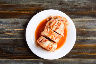 Beyaz tabakta kimçi lahanası, ahşap arka plan, Kore yemeği, üst manzara.