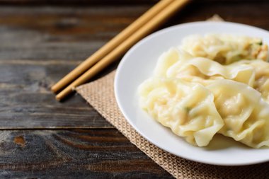 Kıyma, karides, ahşap masa ve Asya yemekleriyle doldurulmuş buğulanmış wonton hamur tatlısı.