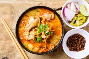 Geleneksel Kuzey Tayland yemeği (Khao Soi), Hindistan cevizi sütlü baharatlı şehriye çorbası ve kızarmış yumurtalı erişte, turşulu hardal yeşili, soğan, kireç, kişniş yaprağı ve yağda kızartılmış kırmızı biber ile tavuk yiyen tavuk. Üst görünüm