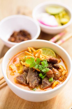 Geleneksel Kuzey Tayland yemeği (Khao Soi), Hindistan cevizi sütlü baharatlı körili şehriye çorbası ve kıtır kıtır kızarmış yumurtalı erişte, turşulu hardal yeşili, soğan, kireç, kişniş yaprağı ve yağda kızartılmış kırmızı biber.