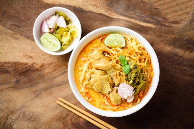 Geleneksel Kuzey Tayland yemeği (Khao Soi), Hint cevizi sütü ve tavuklu baharatlı şehriye çorbası ahşap arka planda, üst manzara
