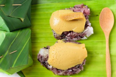 Tayland tatlısı (Khao Niao Sangkhaya), üzerinde yumurta kreması ve taze muz yaprağıyla sarılmış mor yapışkan pirinç.