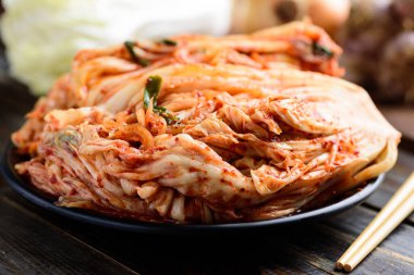 Tabakta kimchi lahanası, ahşap masada çubuklar, Kore yemeği.